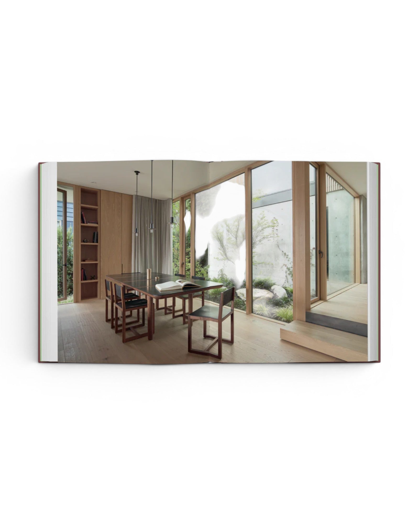 JONES + CO Courtyard Homes book open to a spread showing a modern dining room with floor-to-ceiling windows and garden.