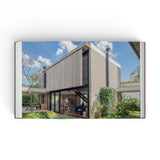 JONES + CO Courtyard Homes book open to a photograph of a modern concrete house with a lush garden courtyard.