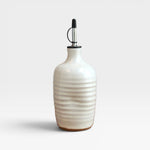 JONES + CO handmade cream stoneware olive oil cruet with a satin finish and ribbed texture on a white background.