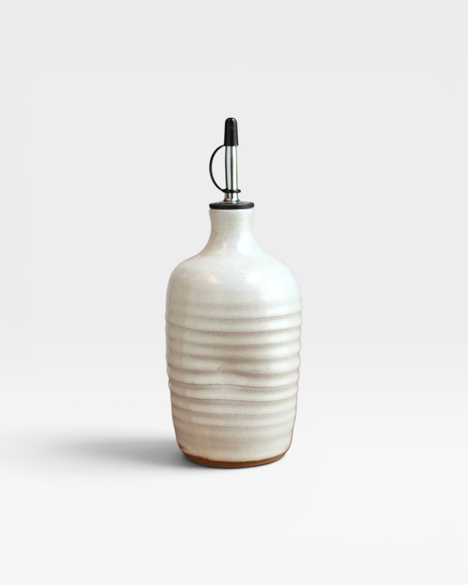 JONES + CO handmade cream stoneware olive oil cruet with a satin finish and ribbed texture on a white background.