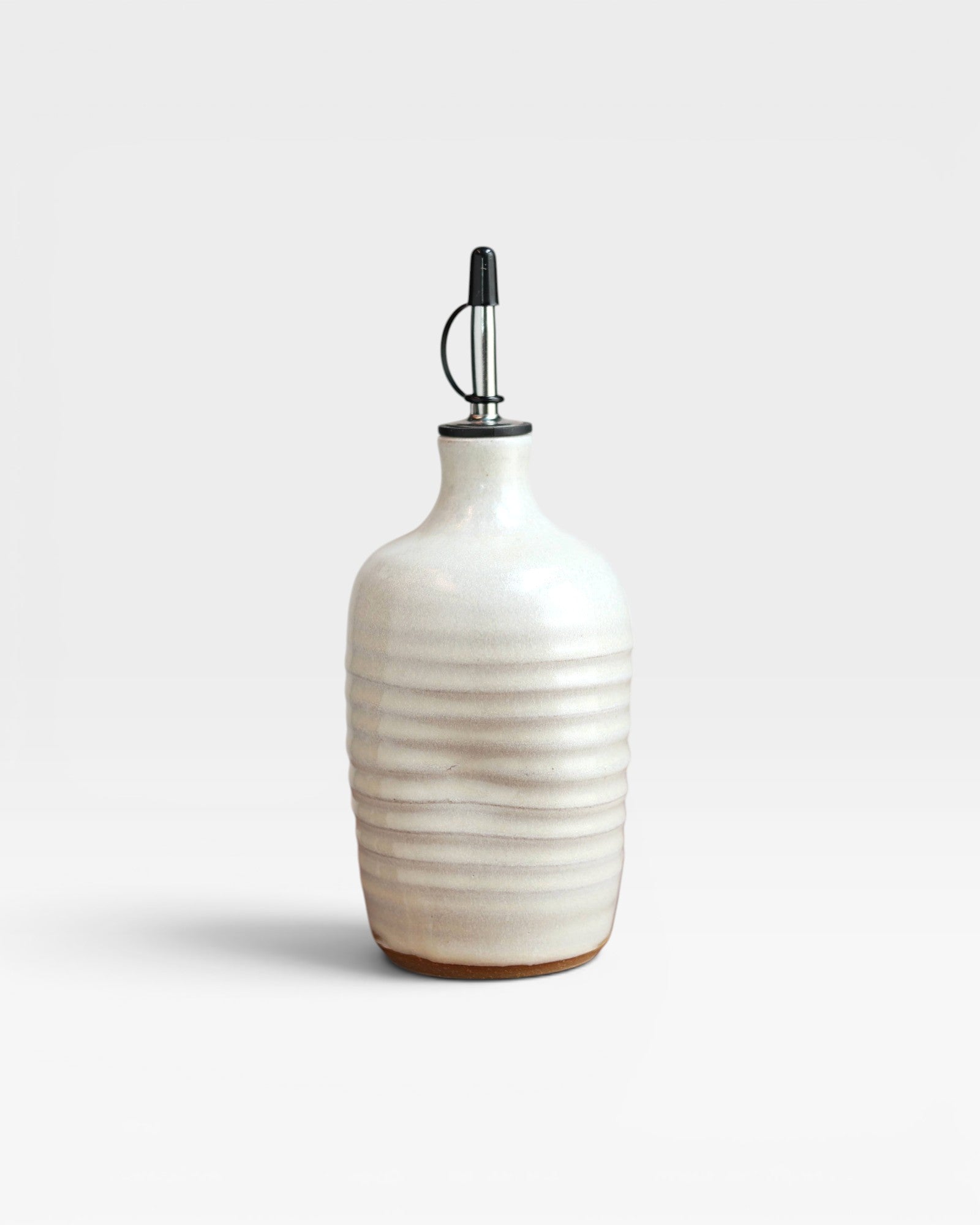 JONES + CO handmade cream stoneware olive oil cruet with a ribbed texture and black pourer spout