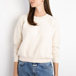 Model wearing a JONES + CO cream-colored textured fleece Ziggy sweatshirt with cropped sleeves and ribbed trim.