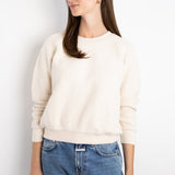 Model wearing a JONES + CO cream-colored textured fleece Ziggy sweatshirt with cropped sleeves and ribbed trim.