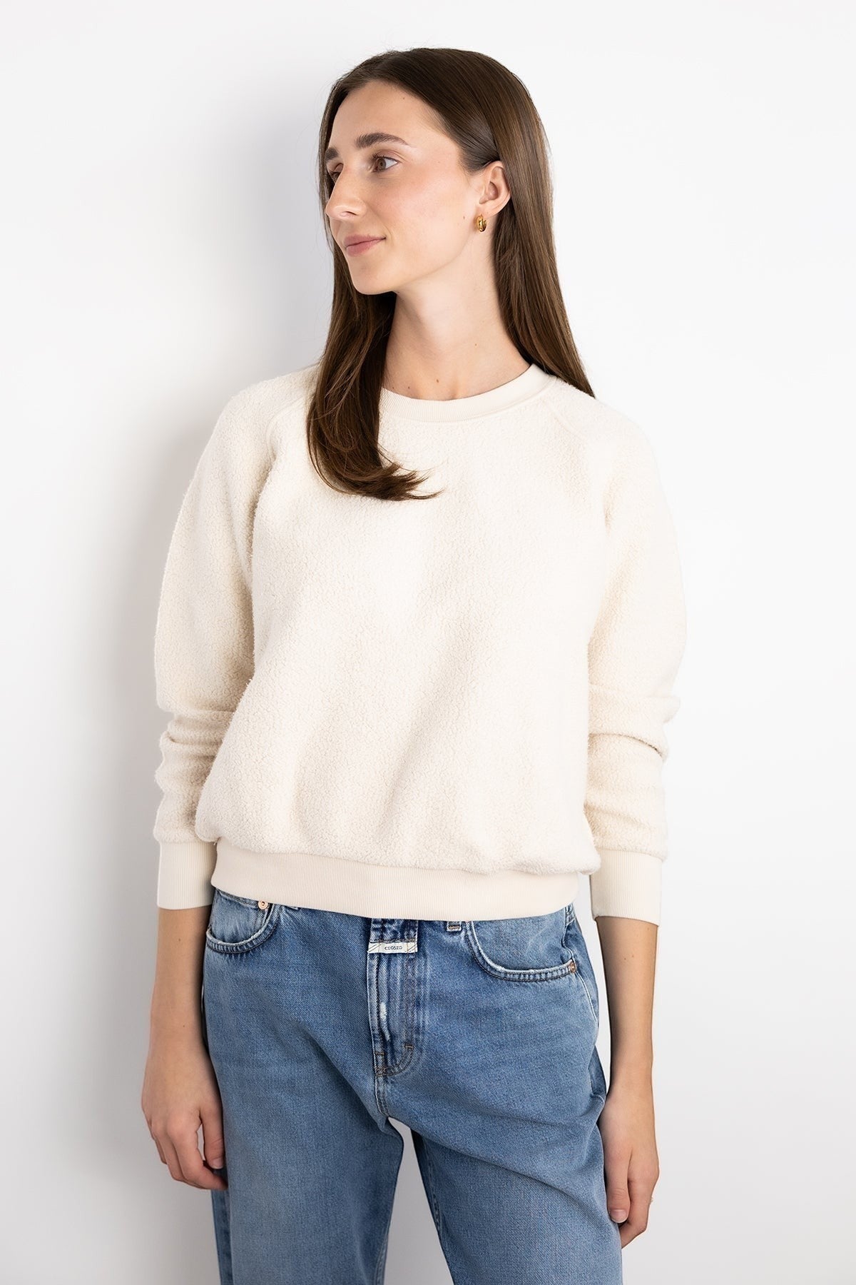 Model wearing a JONES + CO cream-colored textured fleece Ziggy sweatshirt with cropped sleeves and ribbed trim.