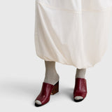 JONES + CO Dahl scarlet leather wedge mules with an angular peep toe and sculptural heel worn with grey socks