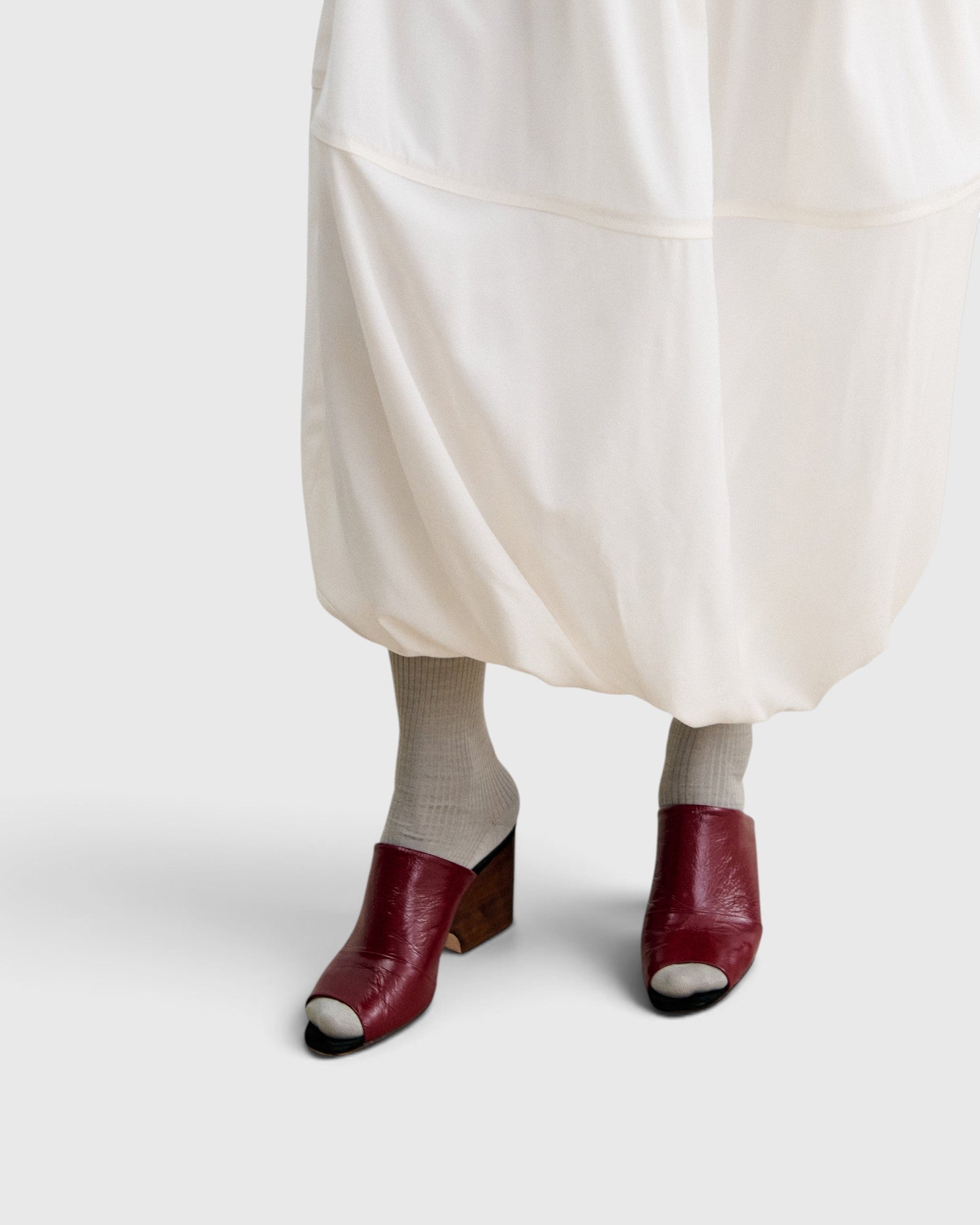 JONES + CO Dahl scarlet leather wedge mules with an angular peep toe and sculptural heel worn with grey socks