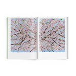 JONES + CO Damien Hirst Cherry Blossoms art book open to a spread featuring vibrant pink and blue floral paintings