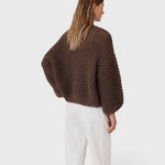 Back view of a model wearing a JONES + CO dark brown chunky alpaca bomber cardigan with a textured pearl knit pattern.