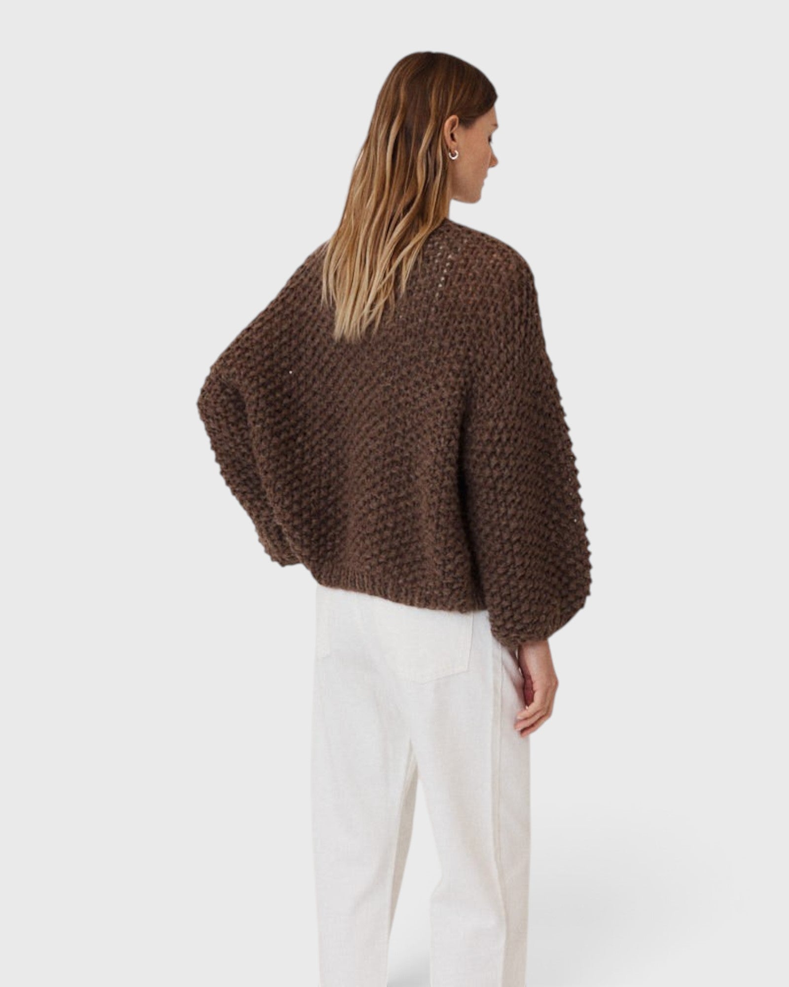 Back view of a model wearing a JONES + CO dark brown chunky alpaca bomber cardigan with a textured pearl knit pattern.