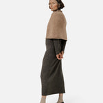 JONES + CO seamless dark fawn alpaca-blend poncho worn over a grey midi dress by a woman in a studio setting