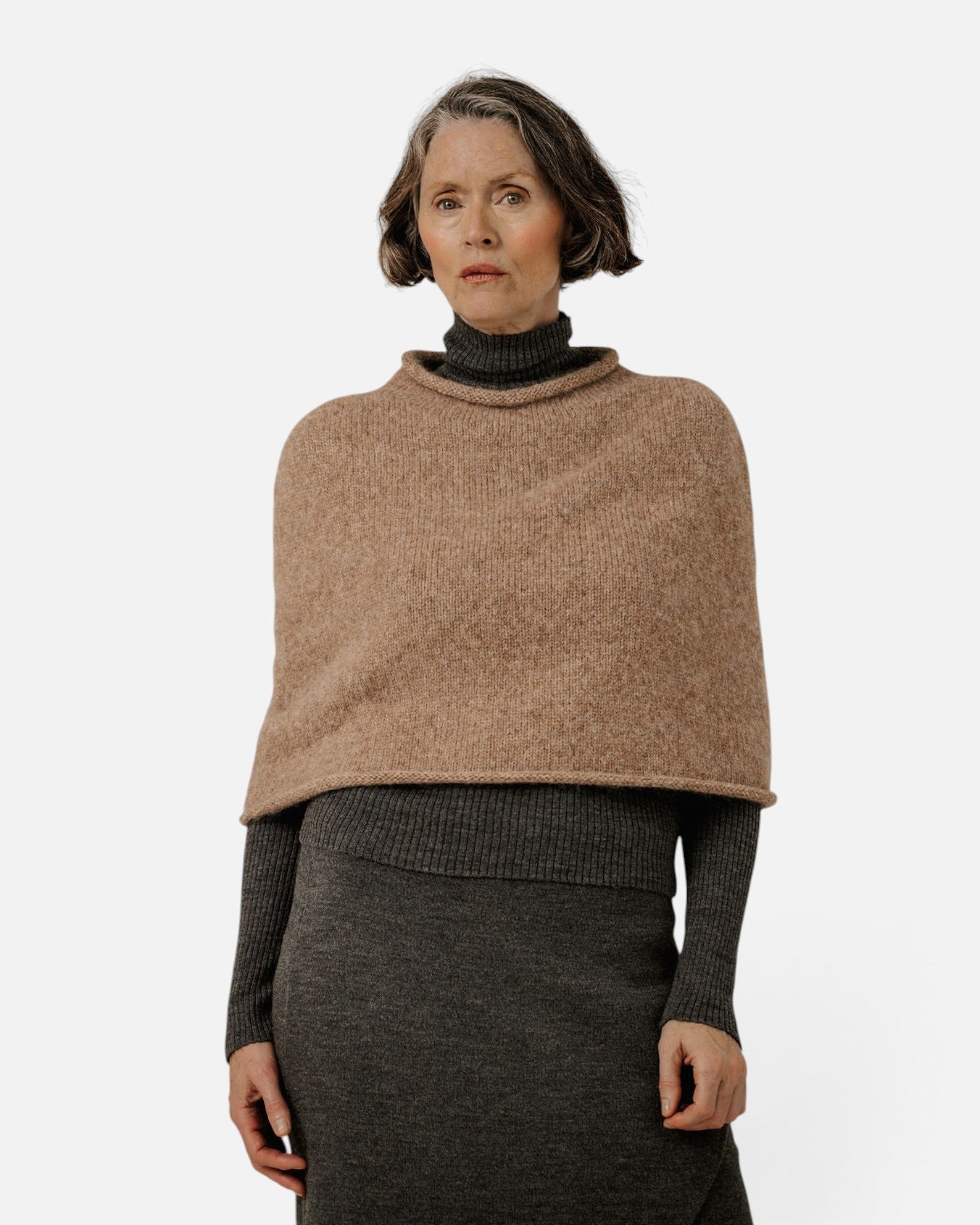 JONES + CO seamless dark fawn alpaca-blend poncho worn over a charcoal turtleneck and skirt