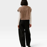 JONES + CO dark fawn alpaca blend button down vest worn over a white long sleeve top and black trousers, back view