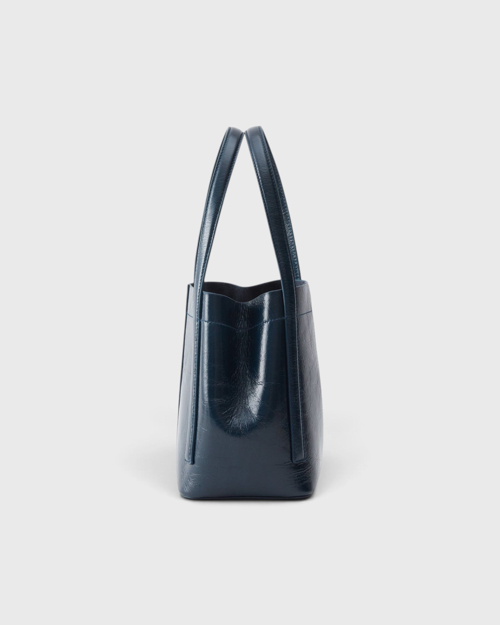JONES + CO Bucket Tool bag in dark indigo lustre leather with vertical paneling and elongated handles, side view.