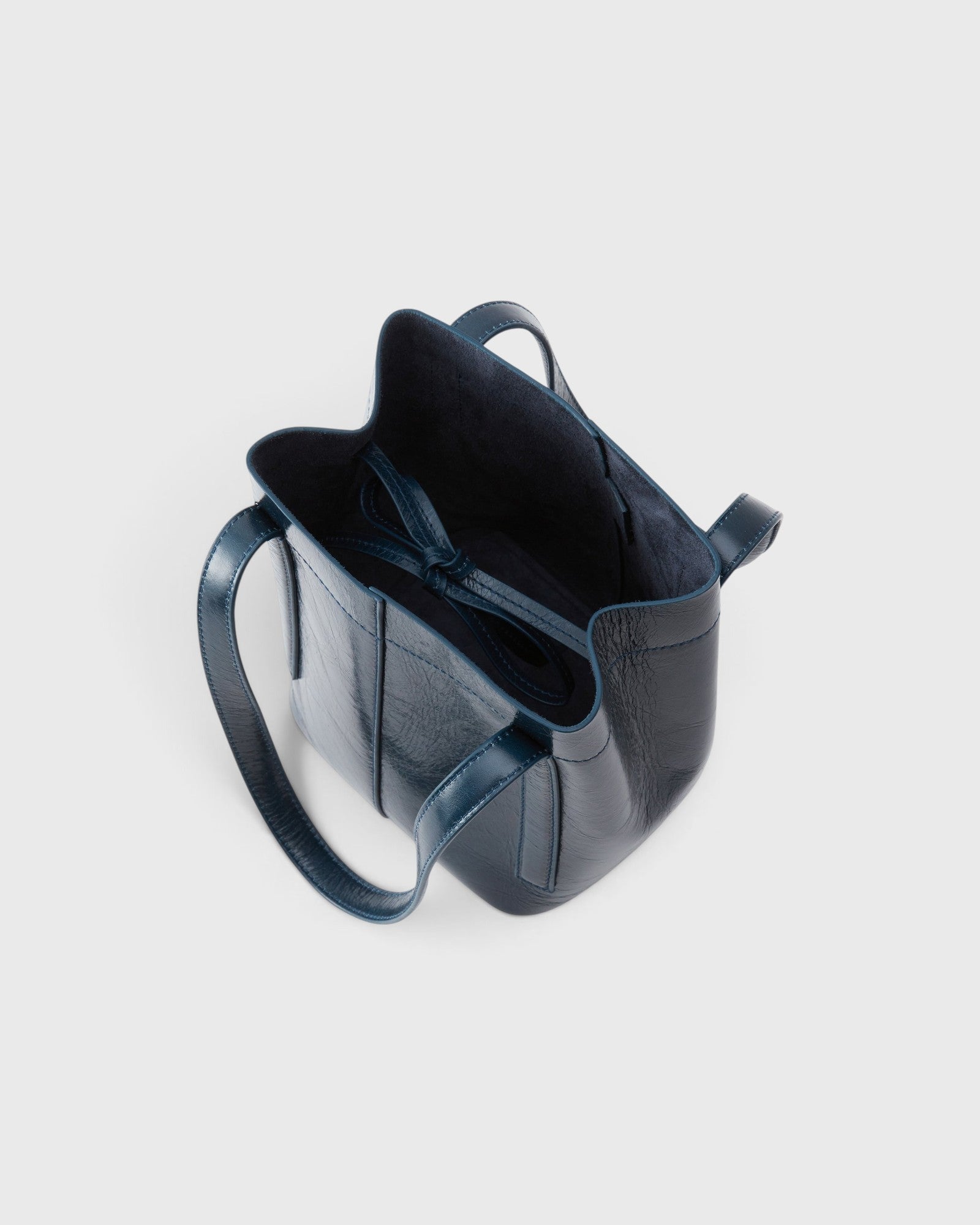 JONES + CO Bucket Tool bag in dark indigo lustre leather with vertical paneling and an open top interior tie closure.