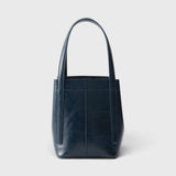 JONES + CO Bucket Tool bag in dark indigo lustre leather with vertical paneling and elongated shoulder handles.