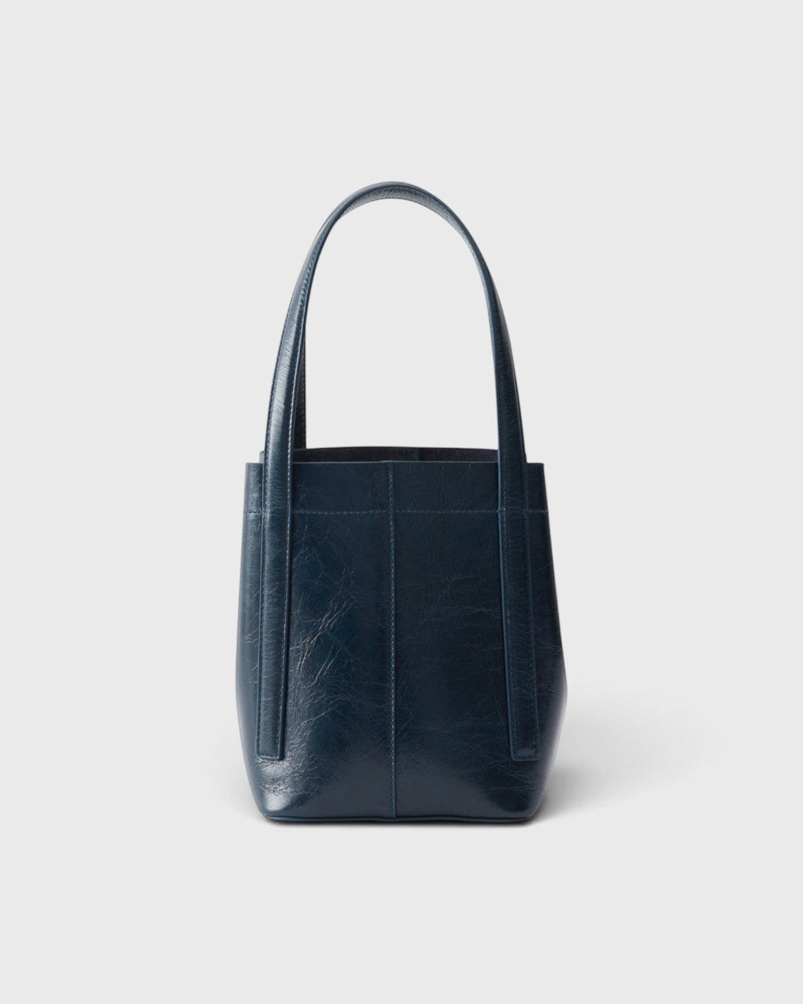 JONES + CO Bucket Tool bag in dark indigo lustre leather with vertical paneling and elongated shoulder handles.