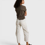 Model wearing JONES + CO dark olive recycled cotton V-neck tee with white trousers, back view