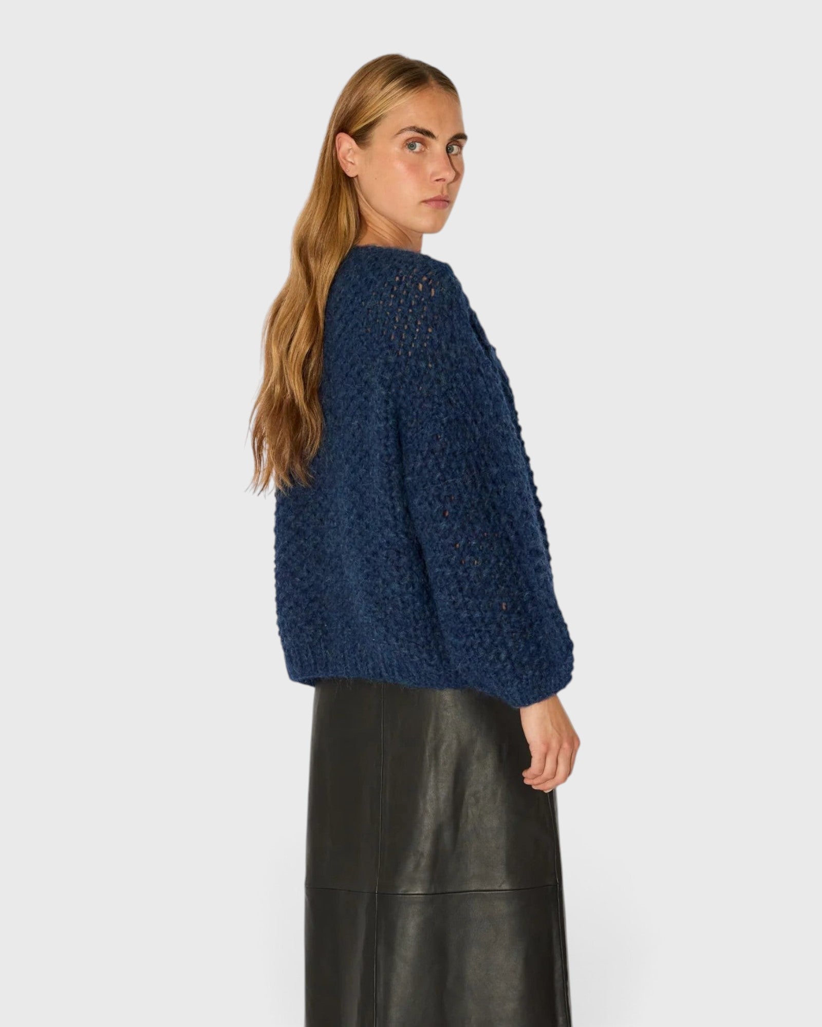 JONES + CO denim blue chunky alpaca bomber cardigan with pearl knit texture worn by a model, side view