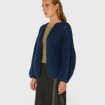 JONES + CO denim blue chunky alpaca bomber cardigan with a textured pearl knit pattern worn by a model.