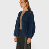 JONES + CO denim blue chunky alpaca bomber cardigan with a textured pearl knit pattern worn by a model.