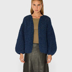JONES + CO chunky denim blue alpaca bomber cardigan with a textured pearl knit pattern worn by a model.
