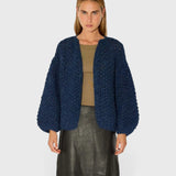 JONES + CO chunky denim blue alpaca bomber cardigan with a textured pearl knit pattern worn by a model.