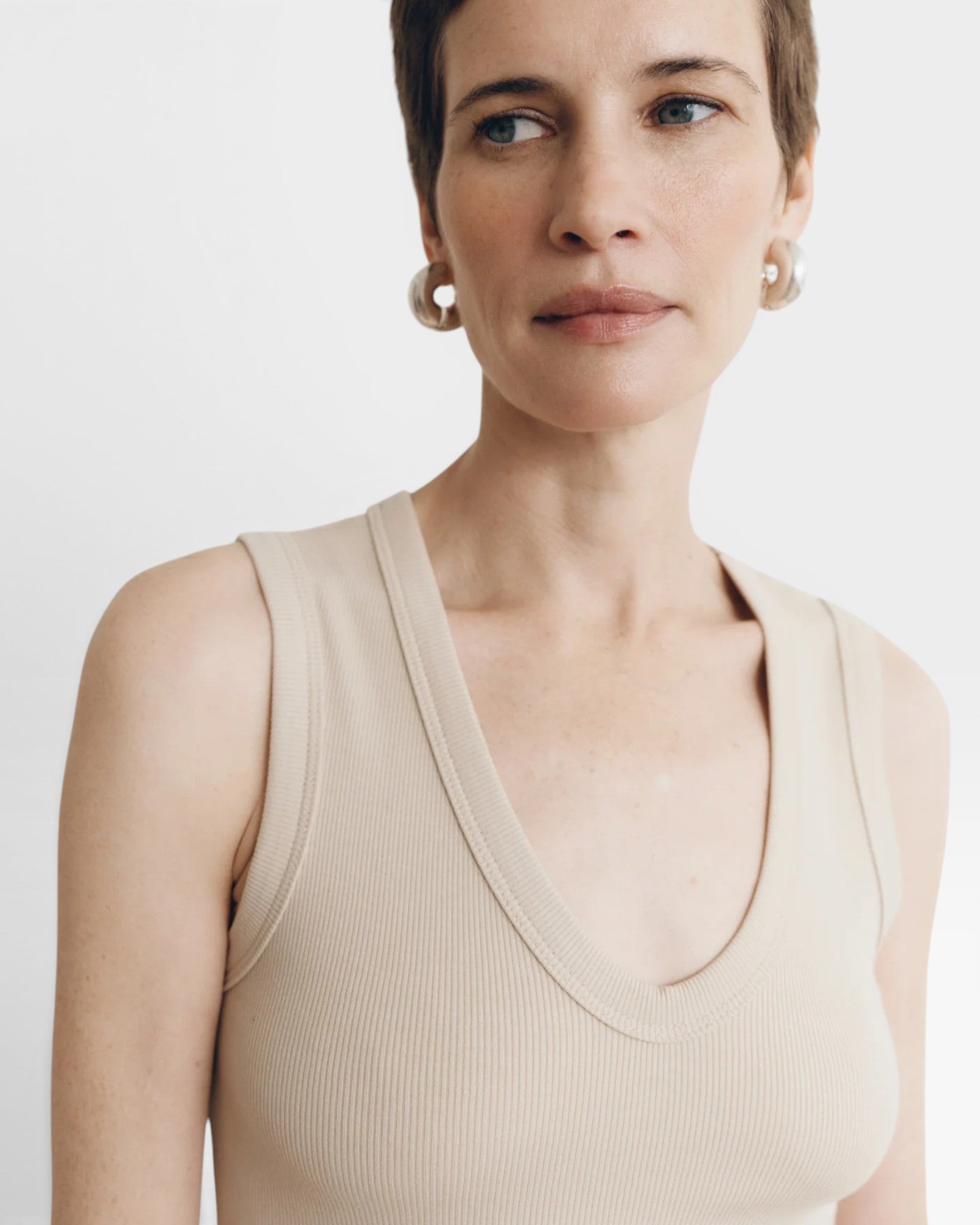 JONES + CO Dune ribbed knit tank top with deep scoop neckline on a woman with short brown hair.