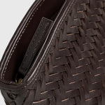 JONES + CO Elin Pouch in espresso brown braided calfskin leather with a zip closure and woven texture.