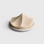 JONES + CO Erode Linden soap in a unique mountain-like shape with botanical flecks, resting on a round stone dish.