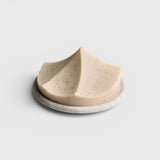 JONES + CO Erode Linden soap in a unique mountain-like shape with botanical flecks, resting on a round stone dish.