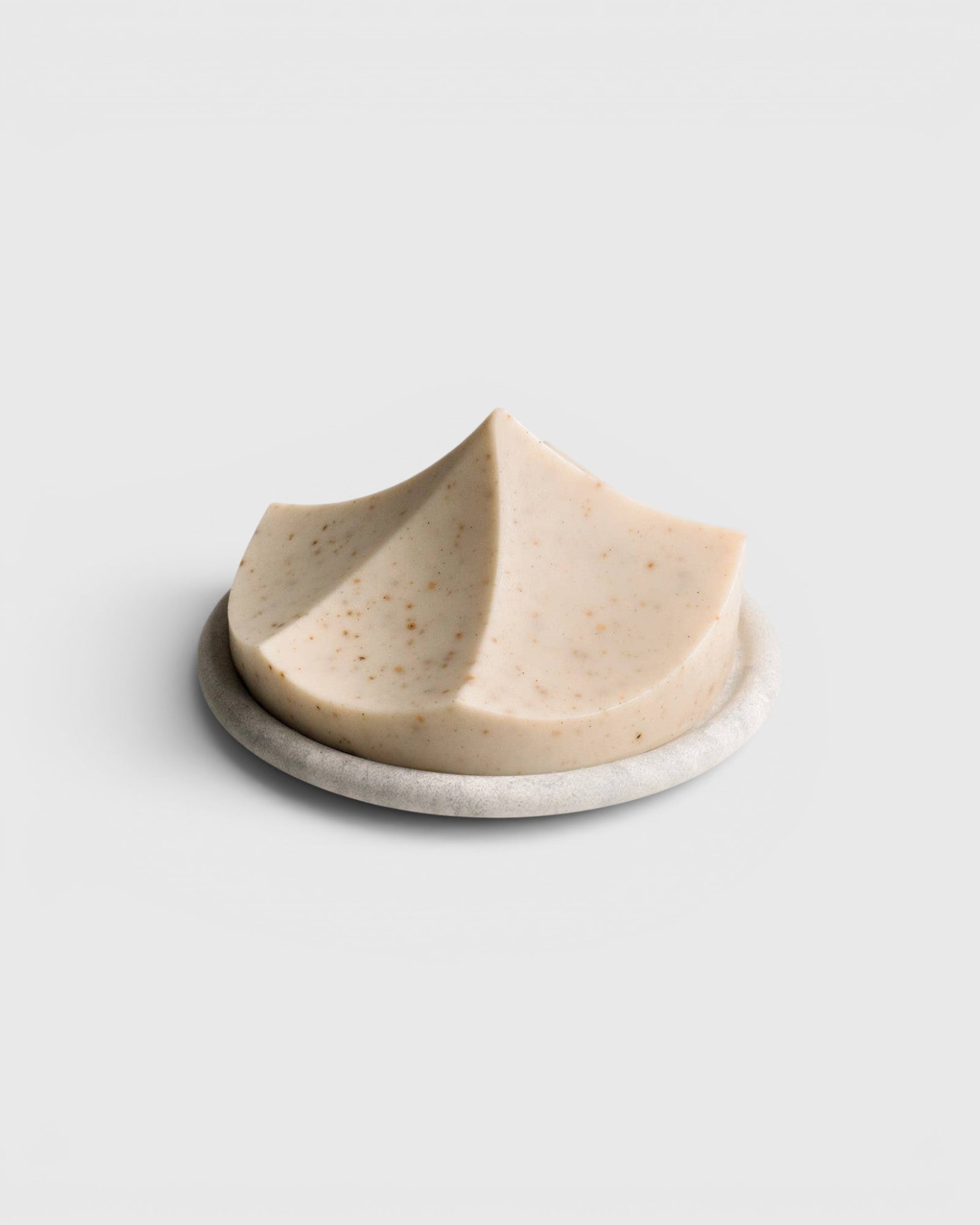 JONES + CO Erode Linden soap in a unique mountain-like shape with botanical flecks, resting on a round stone dish.