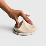 JONES + CO Erode Linden soap in a unique mountain shape on a round ceramic plate, held by a hand.