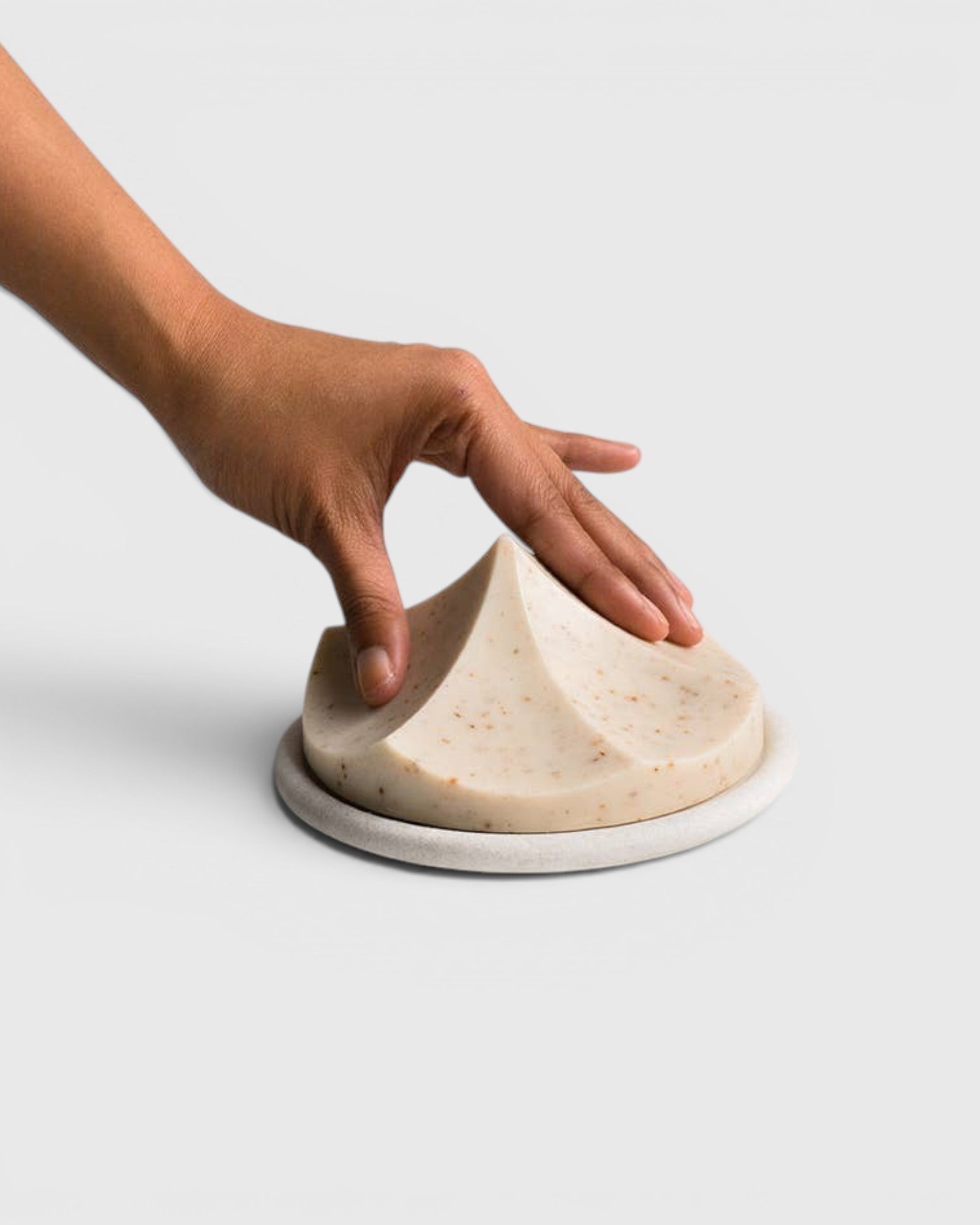JONES + CO Erode Linden soap in a unique mountain shape on a round ceramic plate, held by a hand.