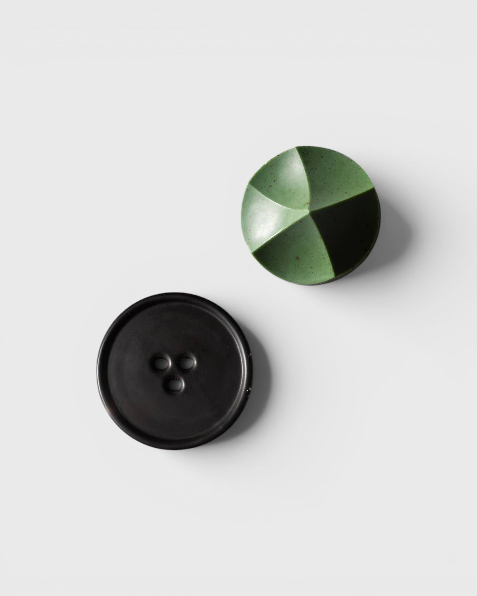 JONES + CO Erode Herbes de Provence soap in a geometric green shape next to a black ceramic Bouton soap dish.