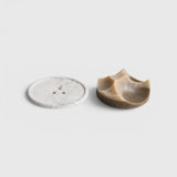 JONES + CO Erode soap in cardamom vetiver scent with a unique sculpted shape next to a white marble Bouton plate.