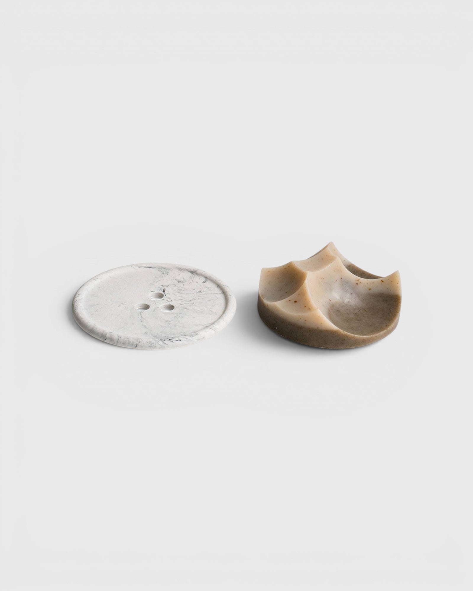 JONES + CO Erode soap in cardamom vetiver scent with a unique sculpted shape next to a white marble Bouton plate.