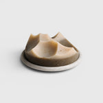 JONES + CO Erode soap in Cardamom Vetiver scent, featuring a unique sculpted shape on a round stone Bouton plate.