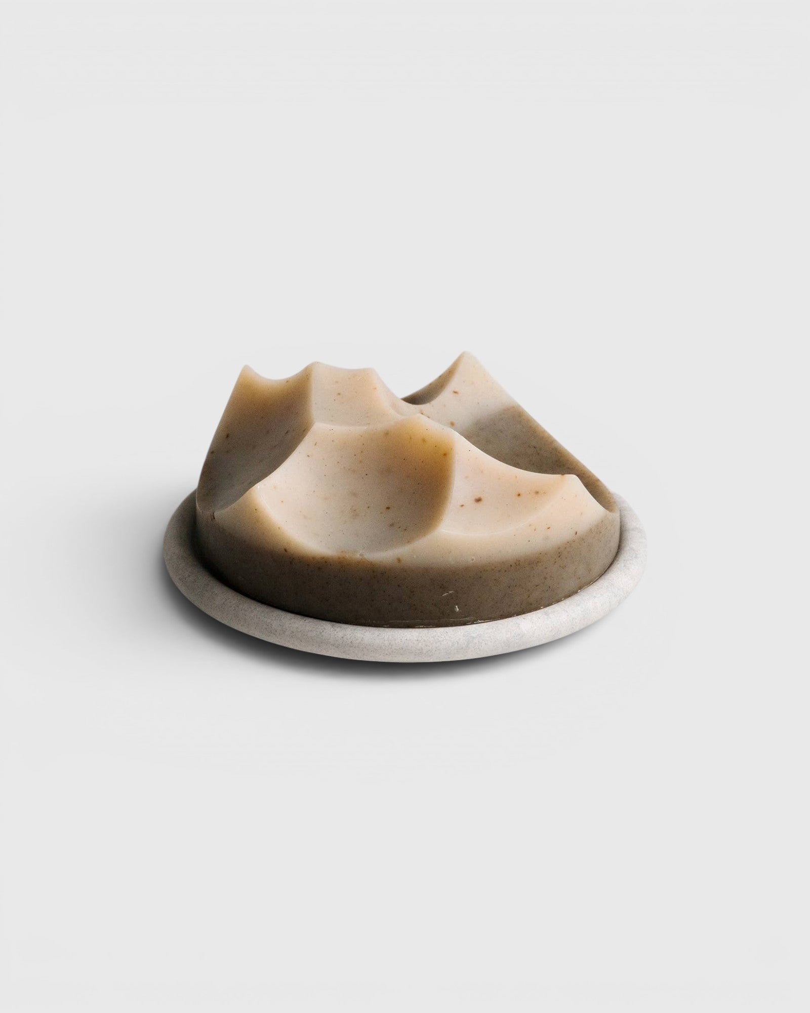 JONES + CO Erode soap in Cardamom Vetiver scent, featuring a unique sculpted shape on a round stone Bouton plate.