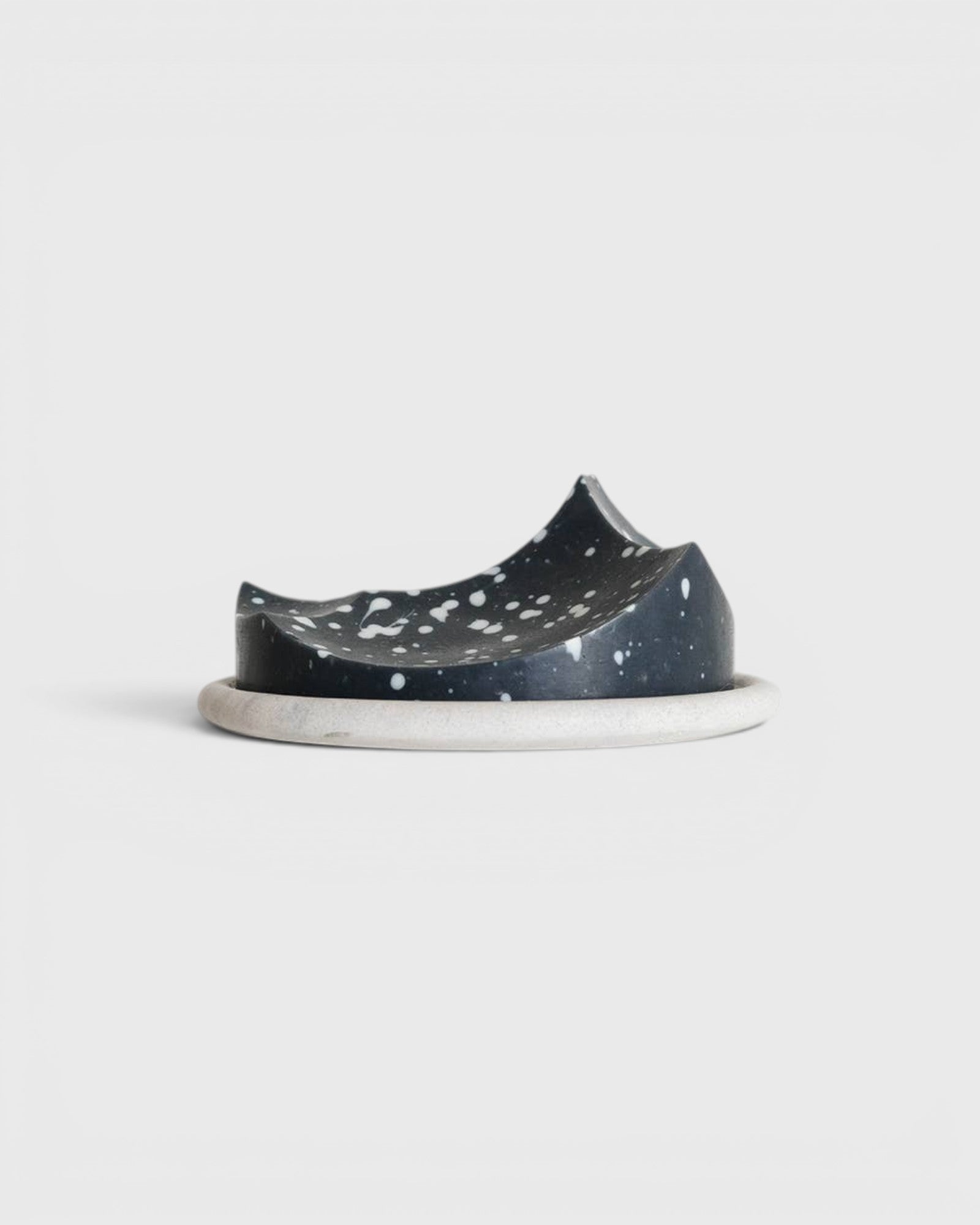 JONES + CO UME Studio Erode Soap Daily Detox in charcoal black with white speckles resting on a round stone plate.