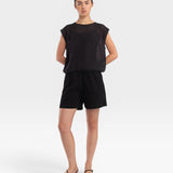 Model wearing a faded black JONES + CO fine mesh boxy tank top with refined trim details and matching black shorts.