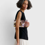 JONES + CO small envelope clutch with abstract floral watercolor print and hinge closure held by a woman