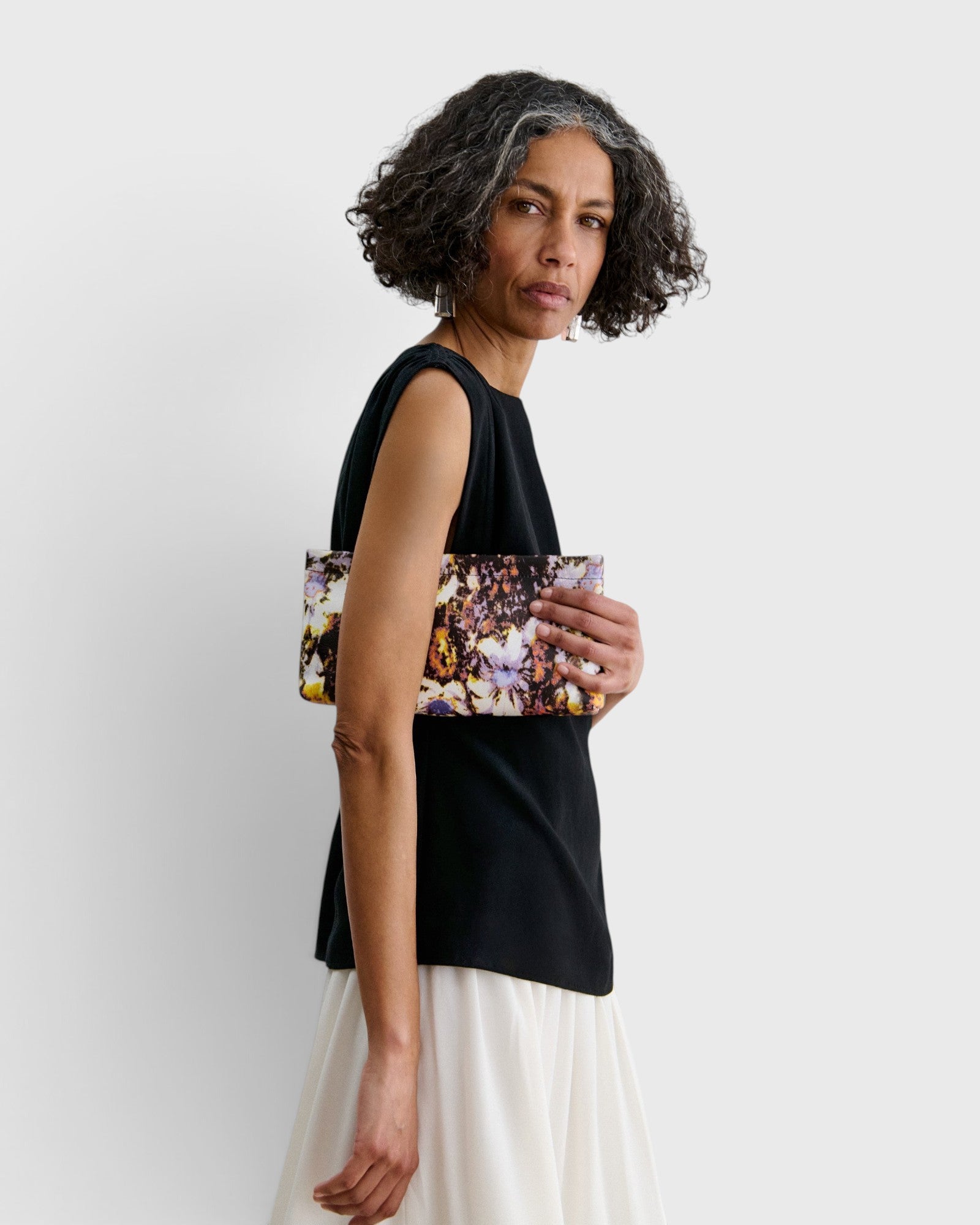 JONES + CO small envelope clutch with abstract floral watercolor print and hinge closure held by a woman