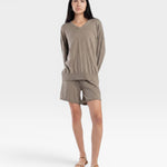 JONES + CO relaxed mid-length knit shorts in fog green with elastic waistband and drawstring. Model is wearing a matching sweater and sandals.