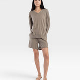 JONES + CO relaxed mid-length knit shorts in fog green with elastic waistband and drawstring. Model is wearing a matching sweater and sandals.