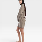 JONES + CO relaxed mid-length knit shorts in fog green with elastic waistband and drawstring. Model is wearing sandals.