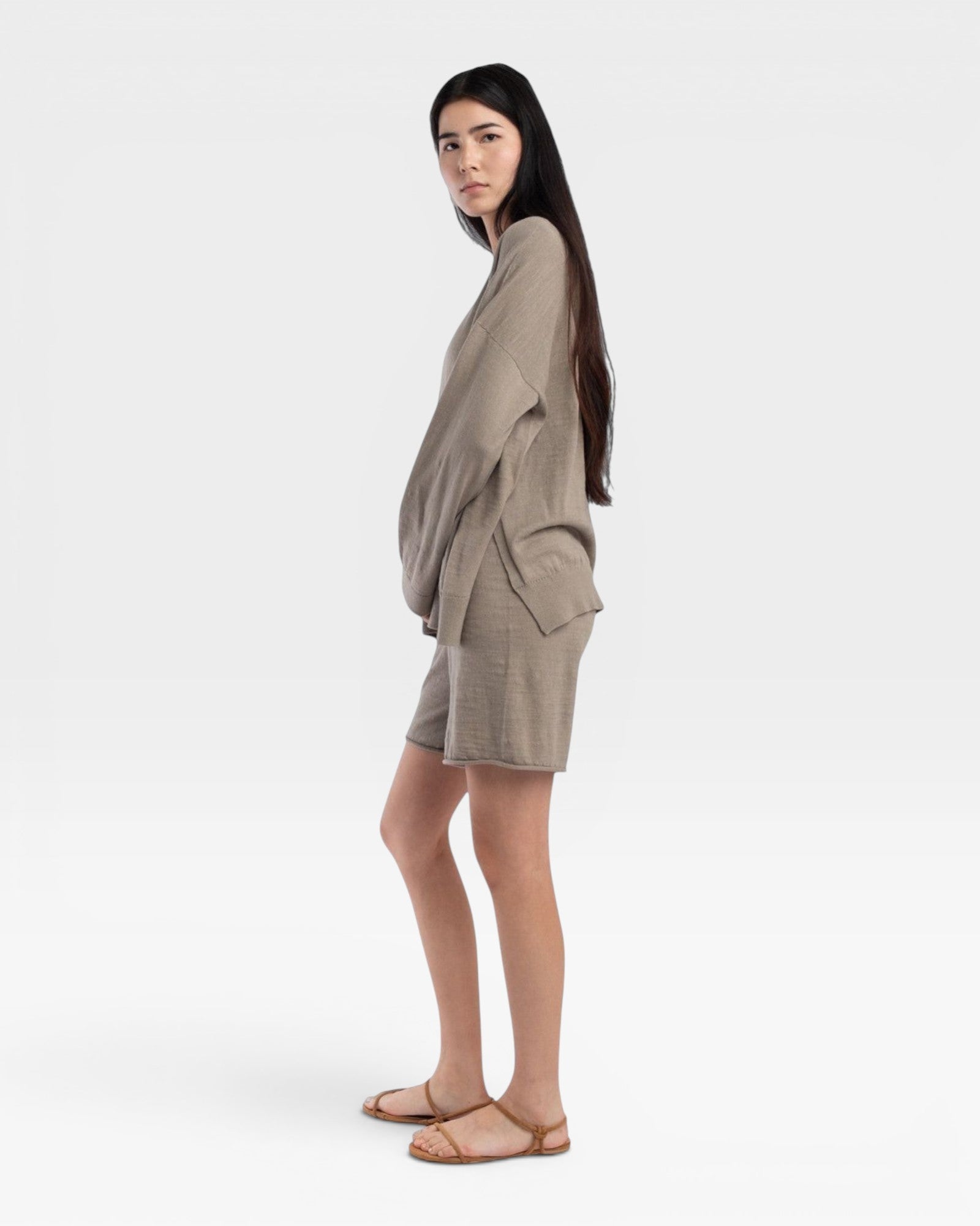 JONES + CO relaxed mid-length knit shorts in fog green with elastic waistband and drawstring. Model is wearing sandals.