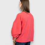 JONES + CO Fond crewneck sweatshirt in guava pink with drop shoulders and raw edge hem, back view on model