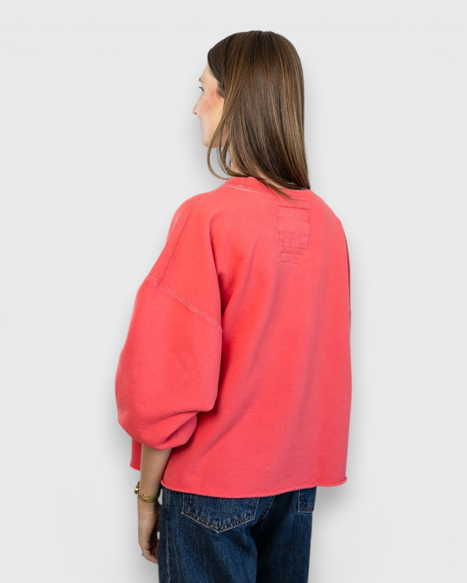 JONES + CO Fond crewneck sweatshirt in guava pink with drop shoulders and raw edge hem, back view on model