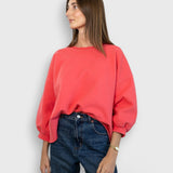 JONES + CO Fond crewneck sweatshirt in guava pink with drop shoulders and cropped sleeves on a model