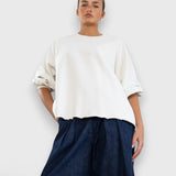 Model wearing JONES + CO Fond crewneck sweatshirt in dirty white with drop shoulders and raw edge hemline.